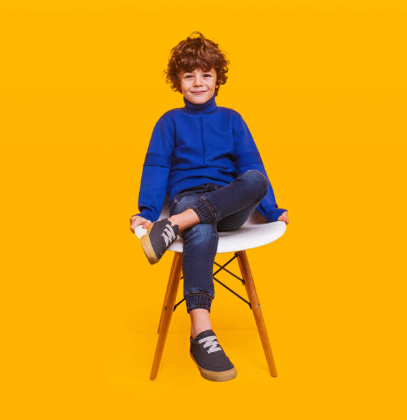 istock Trendy boy sitting on chair 1357570157