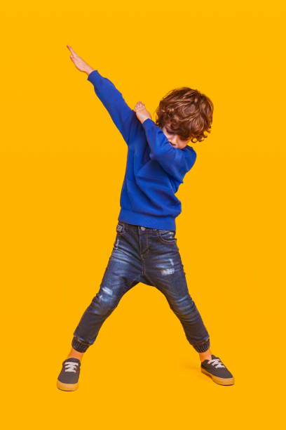 Energetic kid dancing on yellow background stock photo