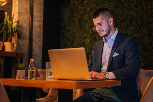 Young handsome businessman working on his laptop while drinking coffee in a cafe