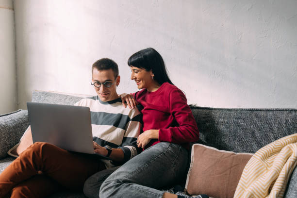 istock A Young Man Sitting On The Sofa With His Girlfriend Showing Her His New Project 1357572888