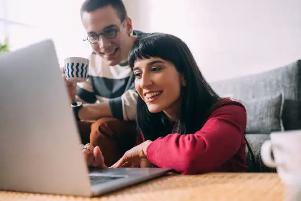 A lovely couple having fun watching something on the laptop.