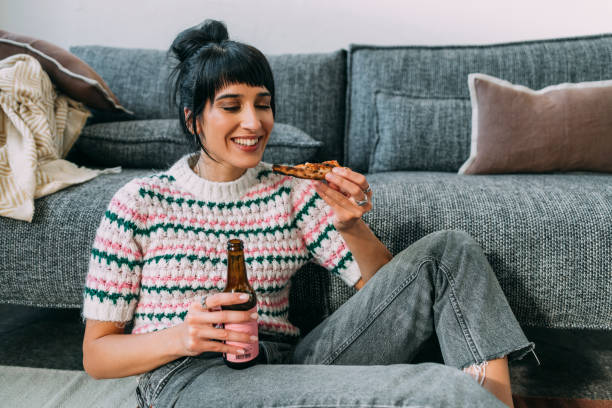 une femme affamée heureuse de manger une pizza et de boire de la bière - bon appetite photos et images de collection