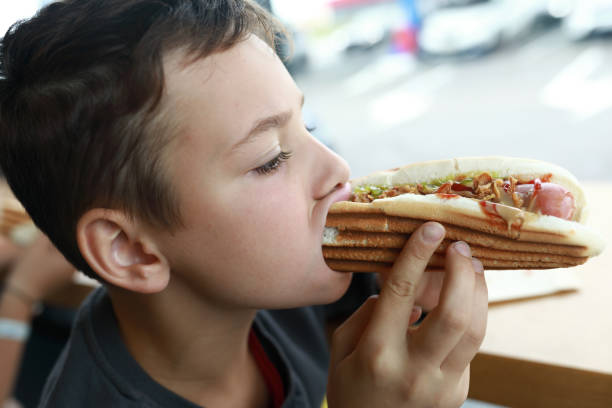 istock Boy eating Hot Dog in restaurant 1357574423