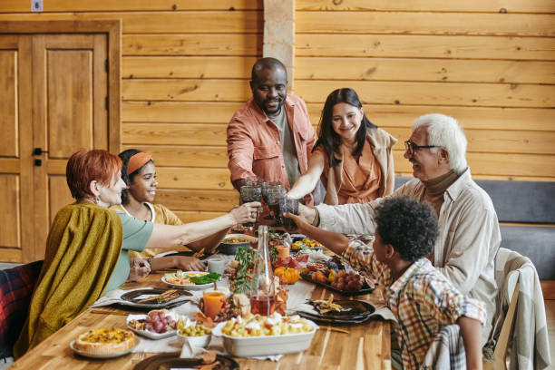 istock Contemporary interracial family clinking with drinks over served table 1357574473