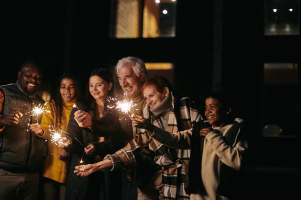 Large happy family of three generations holding sparkling bengal lights stock photo