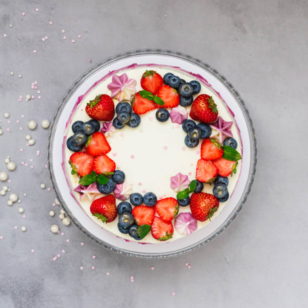 istock Delicate cake garnished with fresh strawberries blueberries on a gray plain background. Festive dessert with berries 1357576481