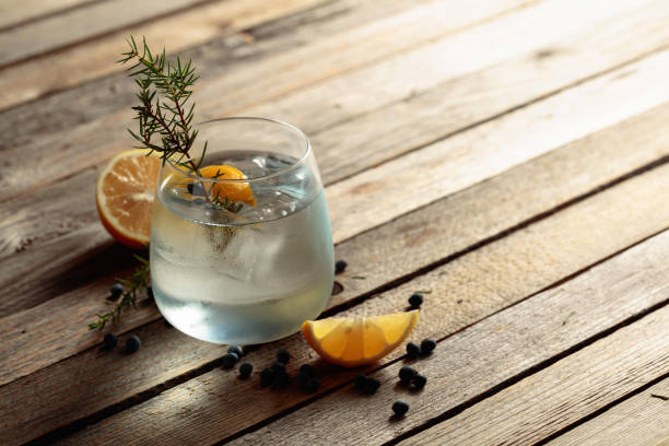 istock Gin tonic cocktail with lemon, juniper branch,  and ice on rustic wooden table. 1357576715