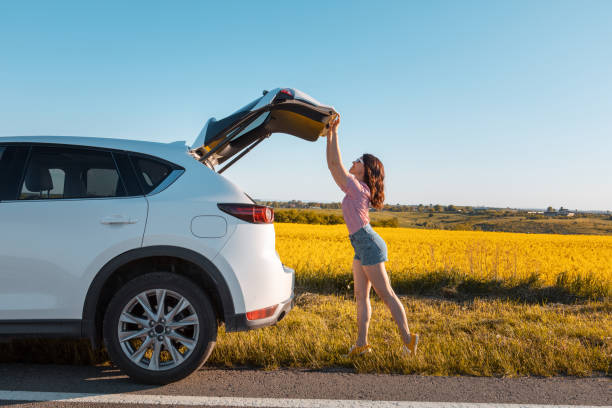 mulher fechando porta-malas de carro estacionado na beira da estrada - sports utility vehicle - fotografias e filmes do acervo