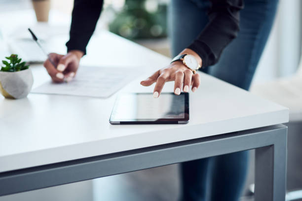 istock Closeup shot of an unrecognisable businesswoman writing notes while using a digital tablet in an office 1357577716