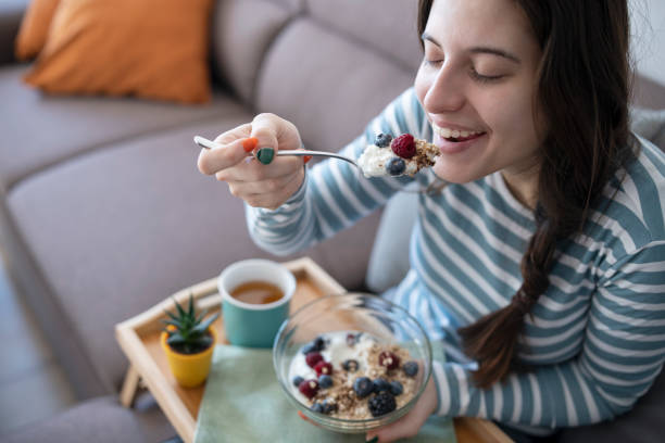 istock Young Woman Enjoying Breakfast On The Sofa At Home 1357579706