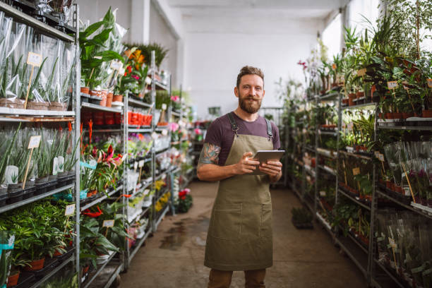 花屋でデジタルタブレットを使った花屋 - florist small business flower shop owner ストックフォトと画像