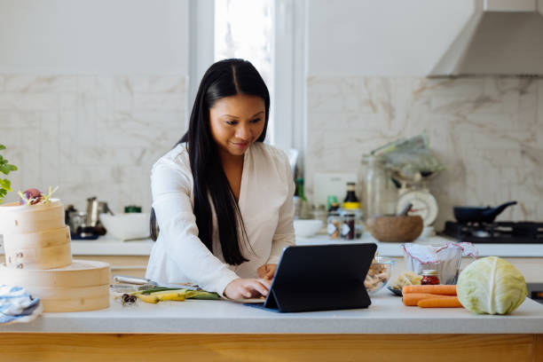 istock Beautiful Woman Using Digital Tablet in her Kitchen 1357580600