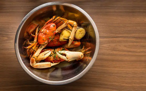Overhead of a bowl with crabs cooking on a wooden background