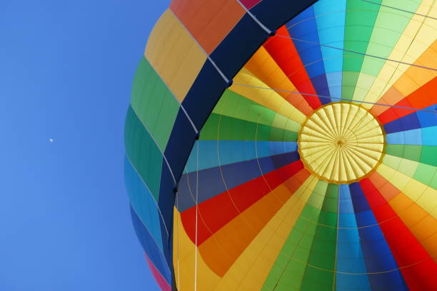 istock View up at hot air balloon and blue sky with very distant moon 1357584090