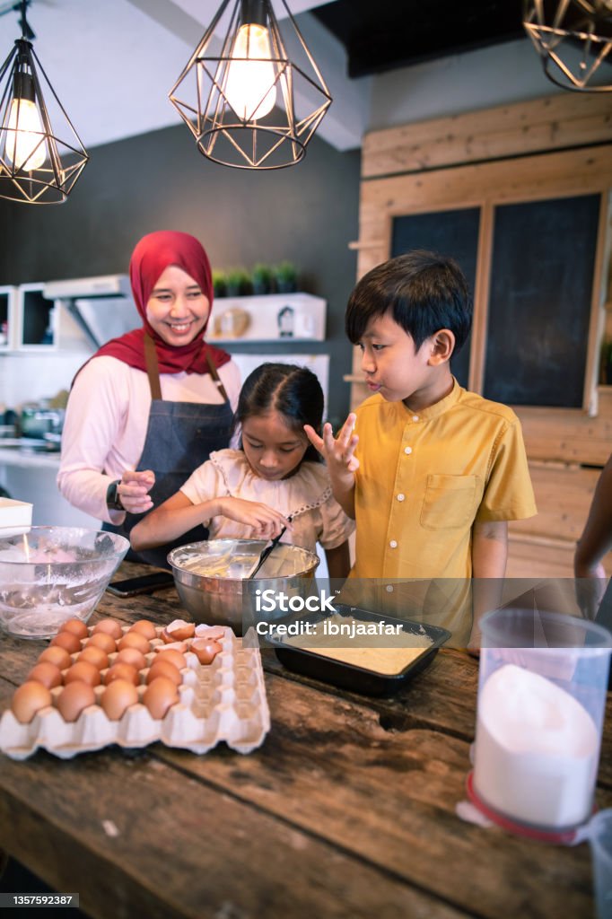 Lets check how is it? The portrait of a family in the kitchen tasting the dough used for making a cake. Cooking Stock Photo