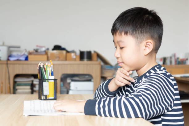 istock Asian boy who are studying in elementary school reading and doing homework by himself at home. 1357592980