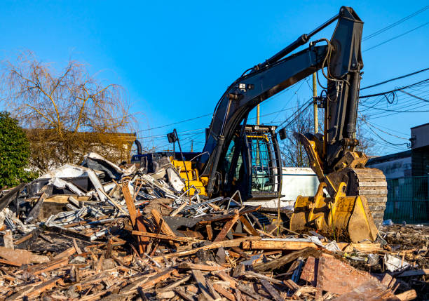 Demolition bulldozer in midst of building rubble. Bucket is down, side view. Yellow construction machine with buildings in background. demolishing stock pictures, royalty-free photos & images