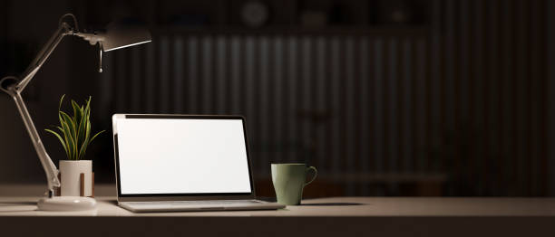istock White screen laptop computer mockup in modern dark office room. 1357597069