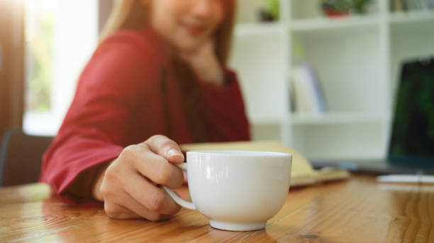 istock Business woman holding coffee cup at her working desk 1357598433