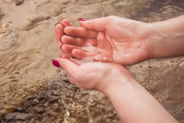 istock Hands picking up water from the river in their palms. Water flows through your fingers 1357599909