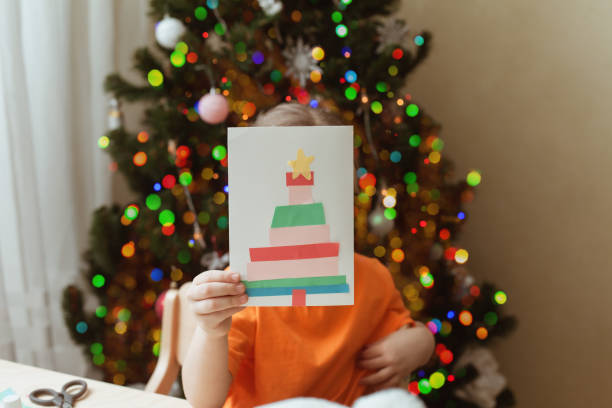 istock Little Girl Making Christmas Card sitting by table 1357605328