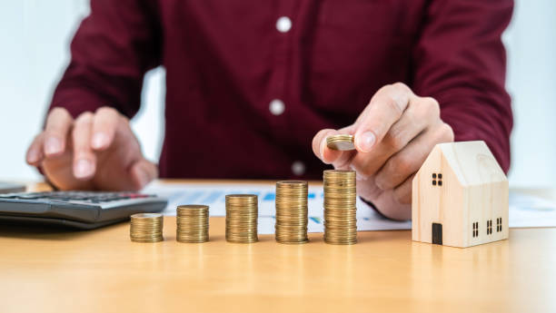 istock Asian business man putting coin increase on coins stacking with house model during using calculator 1357606363
