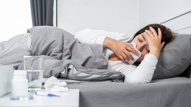 istock Asian woman using tissue cover your mouth to cough, sneeze and touching forehead while feeling sick 1357606677