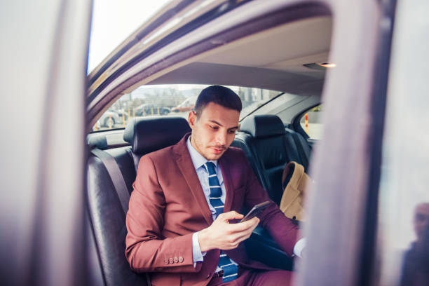 istock Handsome businessman using smartphone in car 1357614094