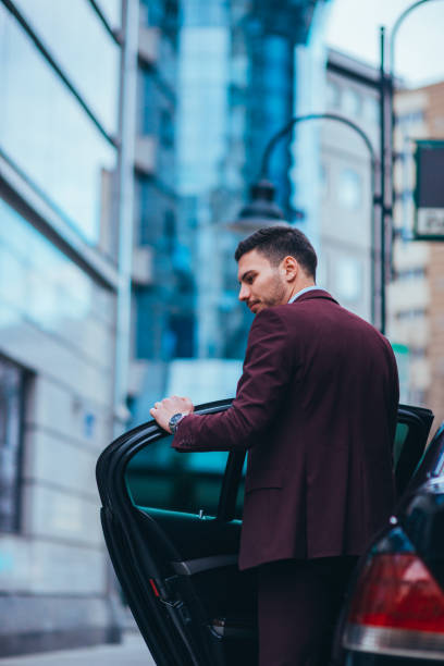 istock Handsome businessman entering and exiting his limo while looking sharp and serious. 1357614187
