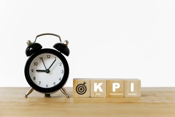 istock KPI, Key Performance Indicator, and dartboard icon on wooden cube with blurred black analog alarm clock on desk 1357616452