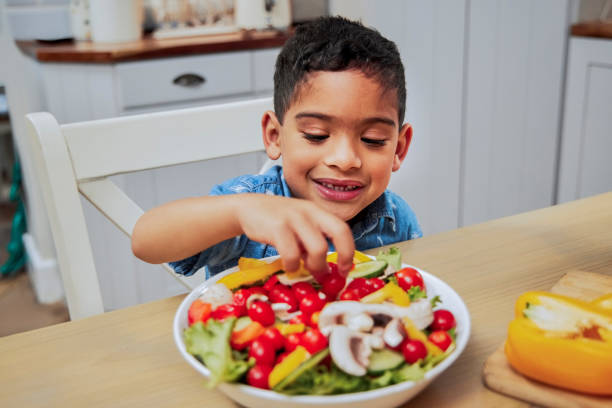 shot of a little boy eating vegetables - comer imagens e fotografias de stock