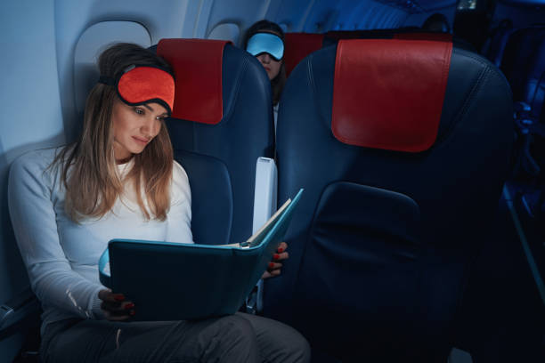 istock Plane passenger in sleep mask reading a book 1357625028