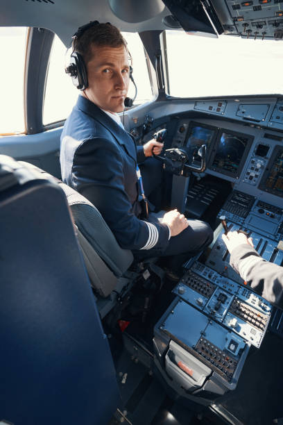 istock Plane captain turning to camera from his seat in cockpit 1357625048