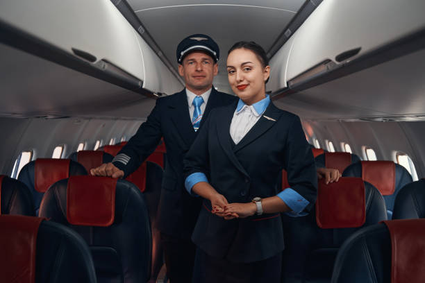 istock Satisfied flight attendant and pilot standing near passenger seats 1357625049