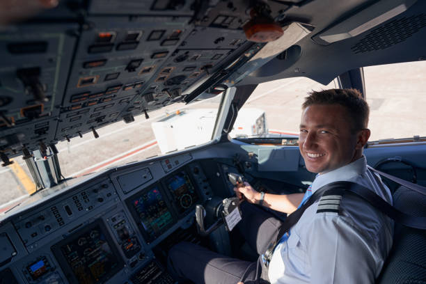 istock Happy airplane pilot smiling to camera with hand on wheel 1357625059