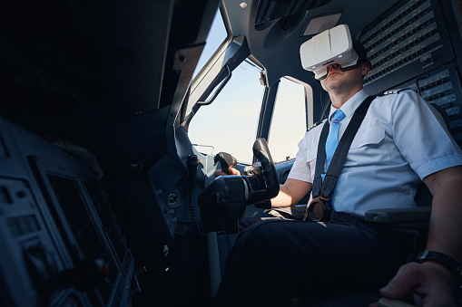 Male co-pilot with VR goggles on his head keeping hand on airplane wheel