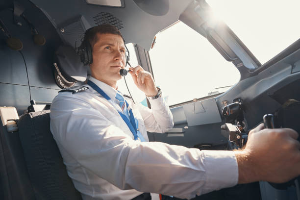 capitán de avión masculino hablando al control de tierra a través del micrófono - pilot cockpit flying business fotografías e imágenes de stock