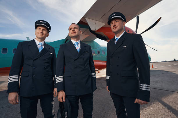 istock Three man in pilot uniforms staring in distance near airplane 1357625081
