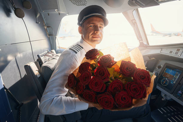 Caucasian pilot sitting with roses in sunlit cockpit