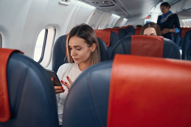 istock Female in plane cabin clicking on her smartphone 1357625112