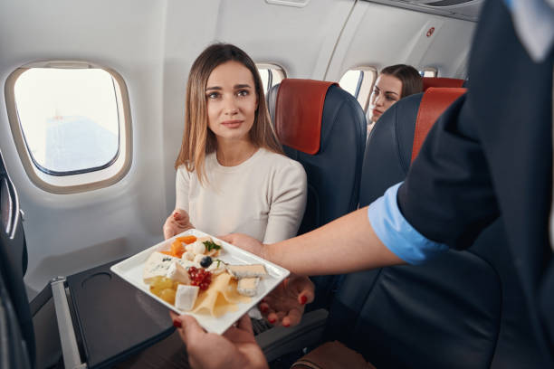 istock Airline hostess passing meal to female passenger 1357625120