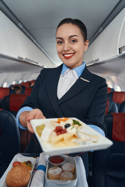 istock Happy flight hostess offering meal from catering trolley 1357625121