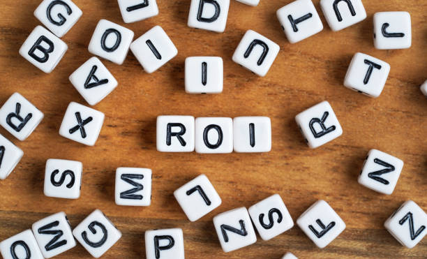 istock Small white and black bead cubes on wooden board, letters in middle spell ROI - Return on investment concept 1357628055