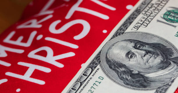istock US 100 dollar banknote and Merry Christmas text on red background for design purpose 1357628403
