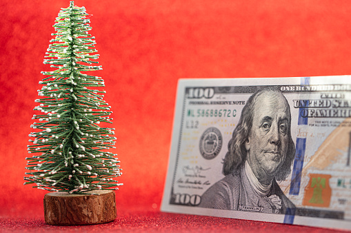 100 dollar bill and toy fir tree on red background for design purpose