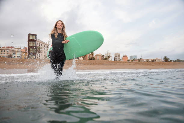 istock Female Surfer With Board Running Into Water 1357629683