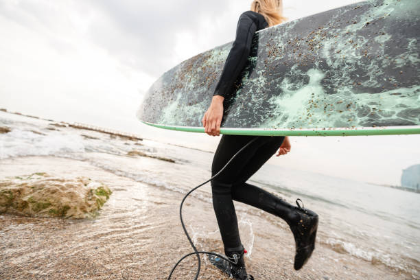 istock Barcelona Female Surfer Walking Into Water With Board 1357629773