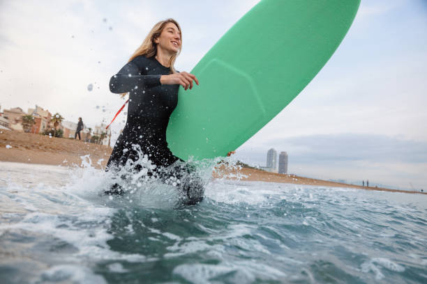 istock Barcelona Female Surfer With Board Running Into Water 1357629811