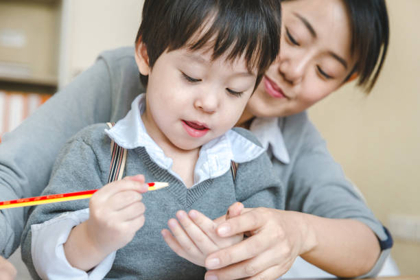 istock Little asian boy doing homework with mom. 1357631042