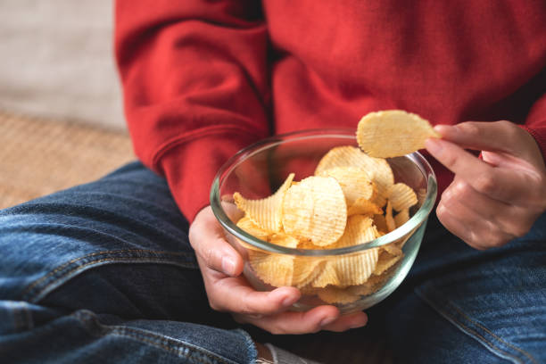 istock a woman picking and eating potato chips at home 1357631291